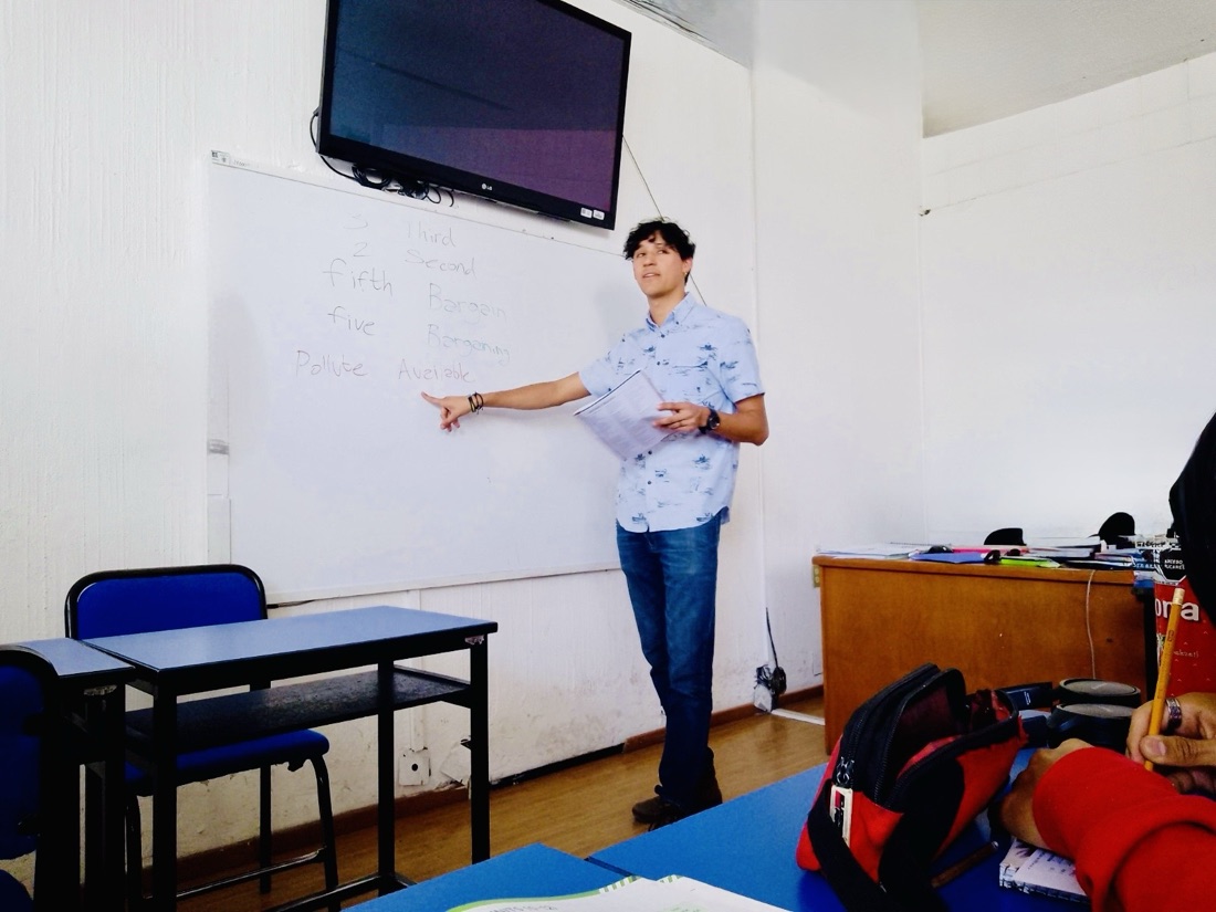 Omar explicando vocabulario en inglés frente a un pizarrón